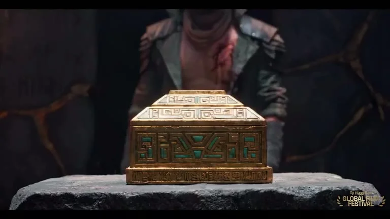 A decorated gold-coloured box rests on a stone surface.